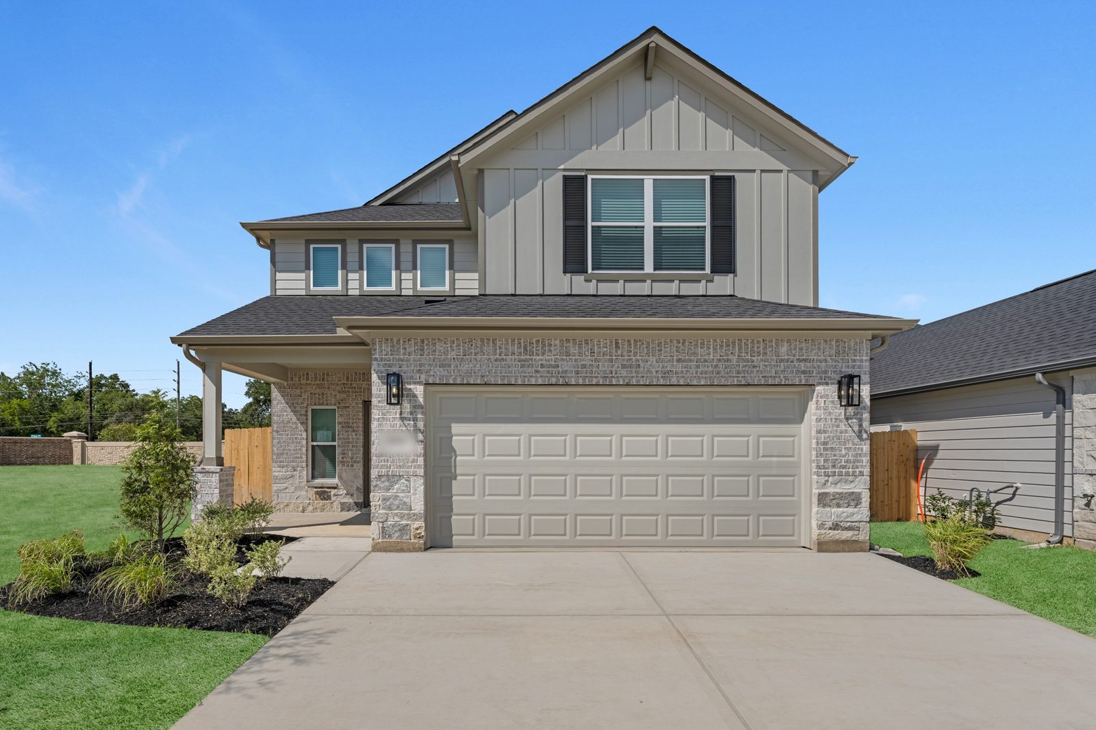 Two-story new home with board-and-batten siding, brick and stone base and a covered front porch