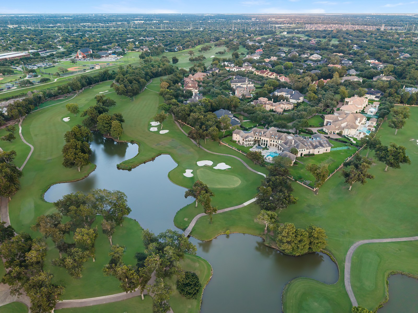 Aerial of estate homes along a golf course with ponds and fairways