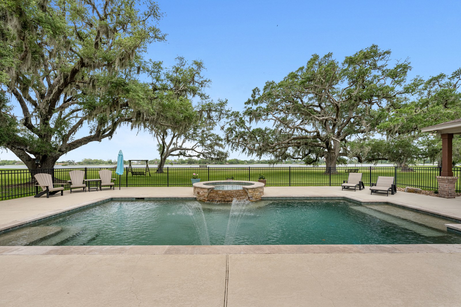 Pool with a spa spillover framed by large live oaks