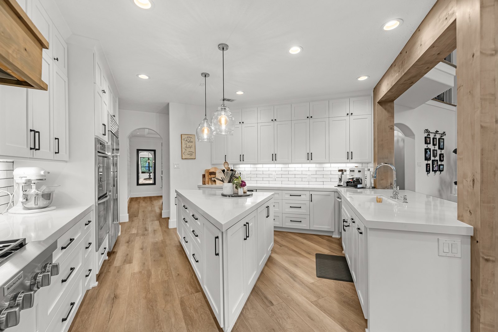 Bright white kitchen with a long island and wood-look floors