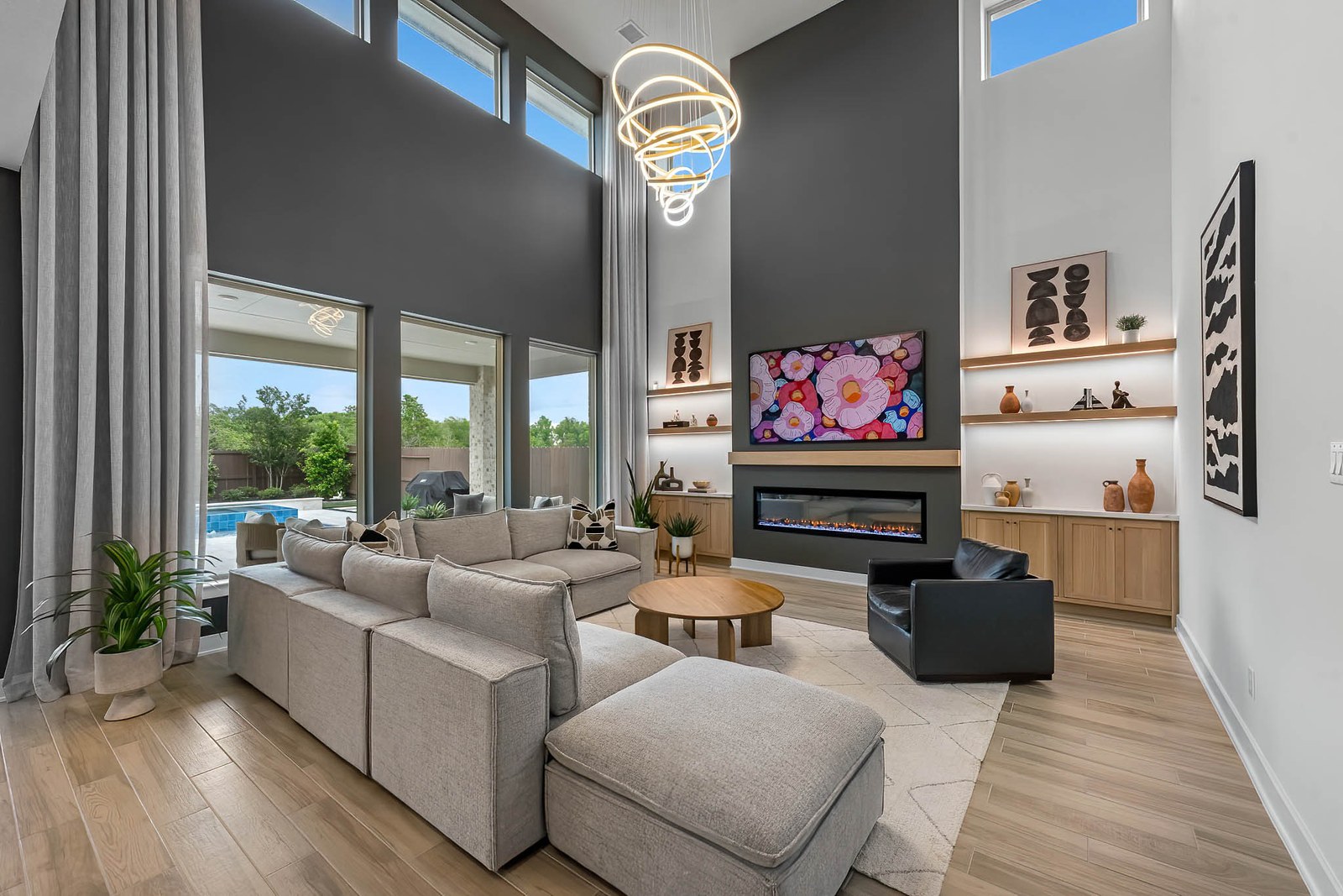Two-story living room with a ring chandelier, linear fireplace and sectional sofa