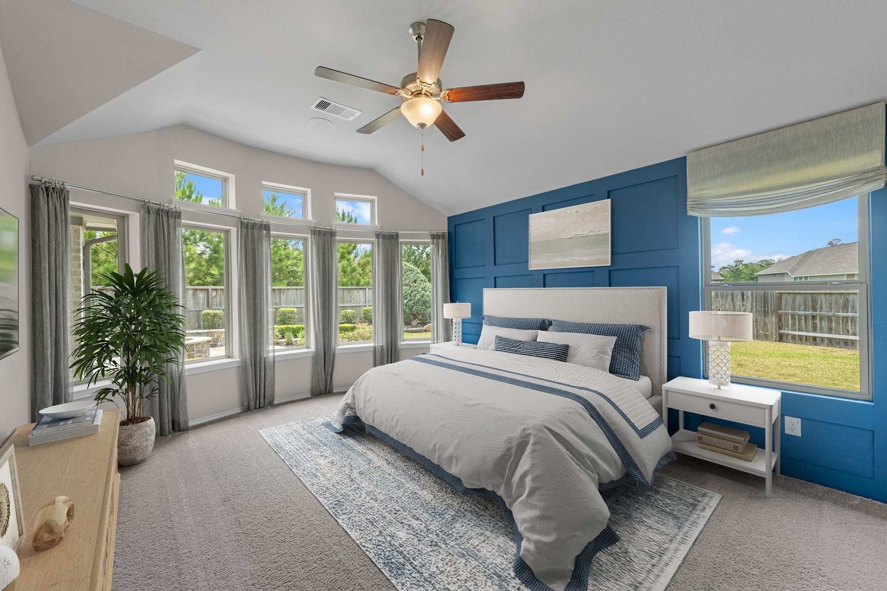 Virtually staged vaulted primary bedroom with a blue accent wall