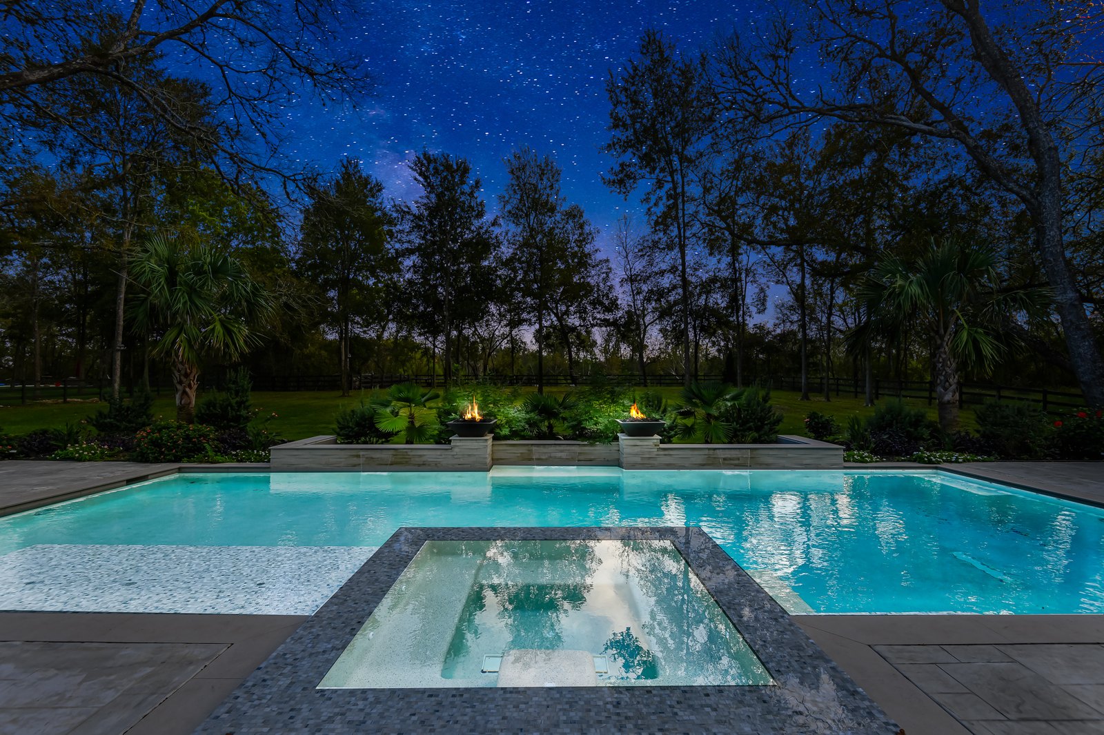 Virtual twilight of a pool and spa with fire bowls under a starry sky